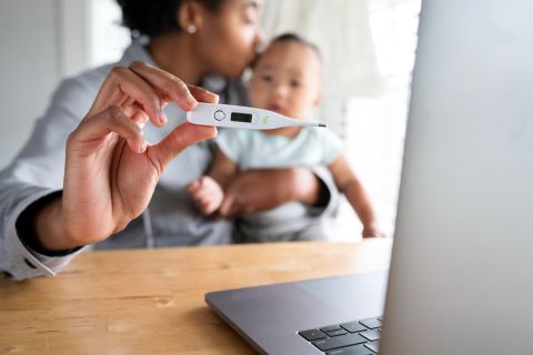 mamma con termometro in mano e neonato con febbre